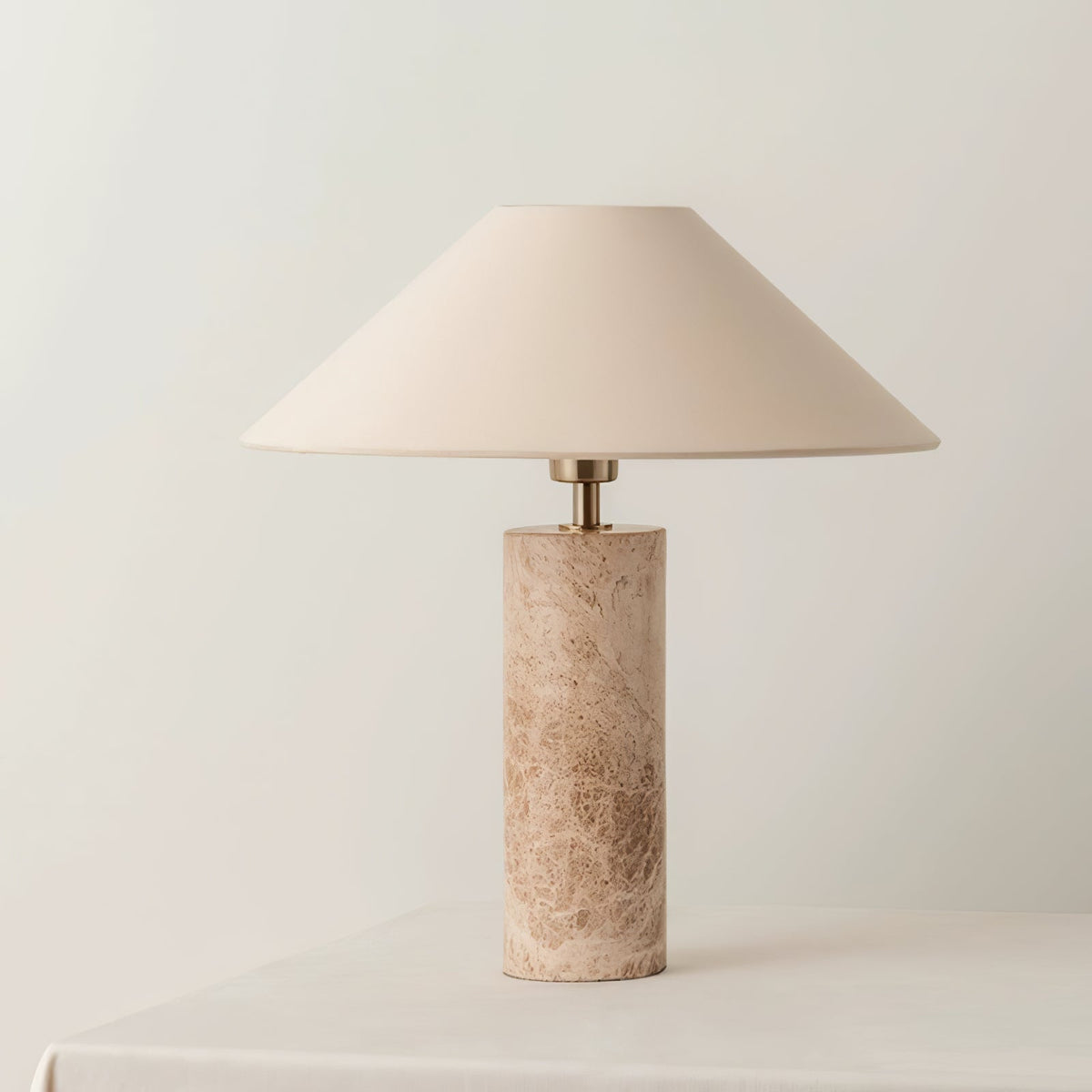 The Clérachic table lamp stands on a raised plinth against a plain background, its ivory shade lit warmly.