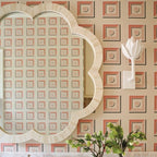 White plaster Kristy sconce on patterned pink wallpaper beside a scalloped bone-inlay mirror.