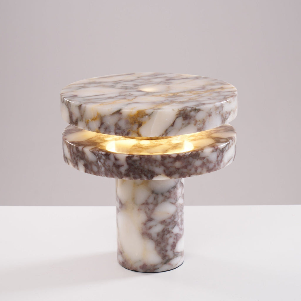 Clérachic lamp lit at a slight angle on the plain backdrop, its two marble discs and column base fully in view.