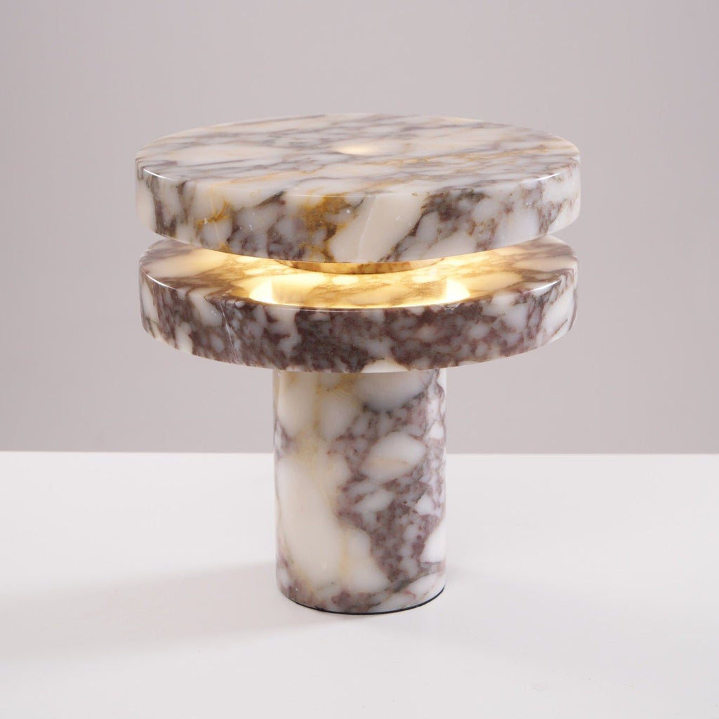 Another angled studio shot of the lit Clérachic lamp, the marble discs catching soft highlights from above.