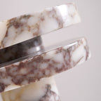 Extreme close-up of the Clérachic lamp's marble veining where the two discs meet, photographed from above at an angle.