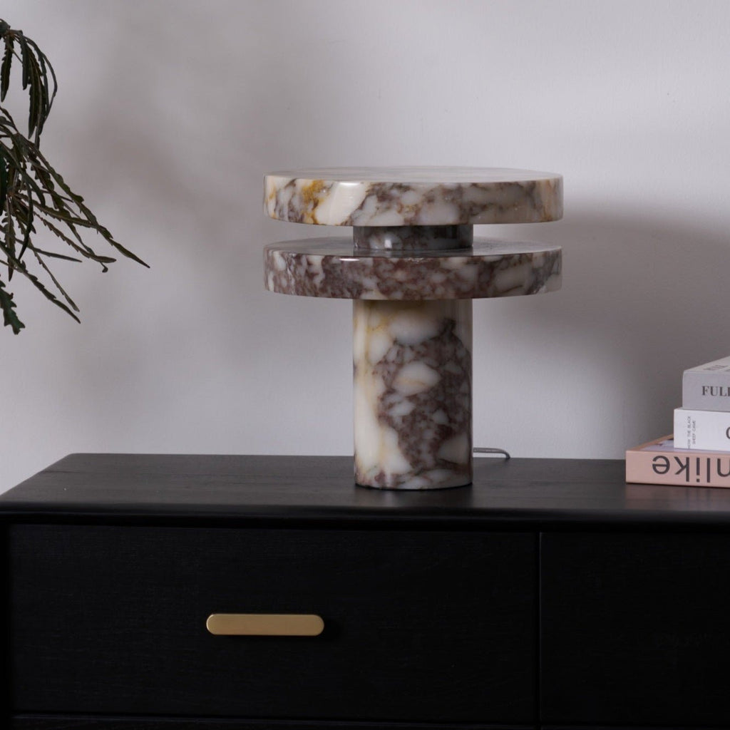 Tighter crop of the lit Clérachic lamp on the dresser, its glowing gap centred between the branch and the book stack.