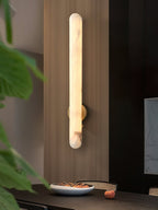 The sconce lit on wood panelling above a dining table set with a shallow bowl.