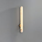 The sconce lit on grey, warm light running the full length of the rounded alabaster bar.