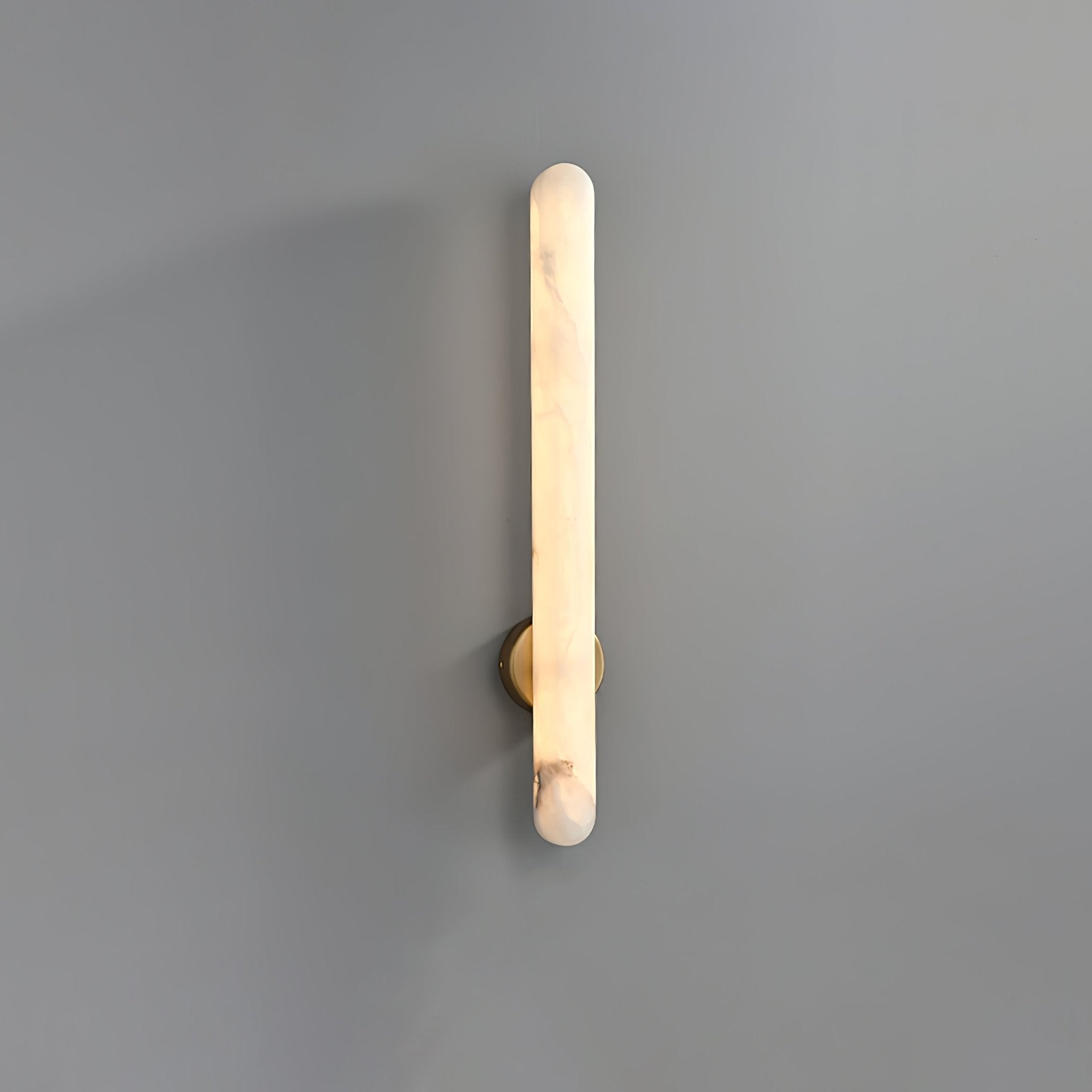 The sconce lit on grey, warm light running the full length of the rounded alabaster bar.