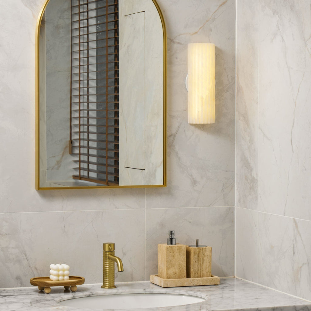 Close view of the lit Orcarion wall light on marble tile, showing the white oval bracket at its centre.
