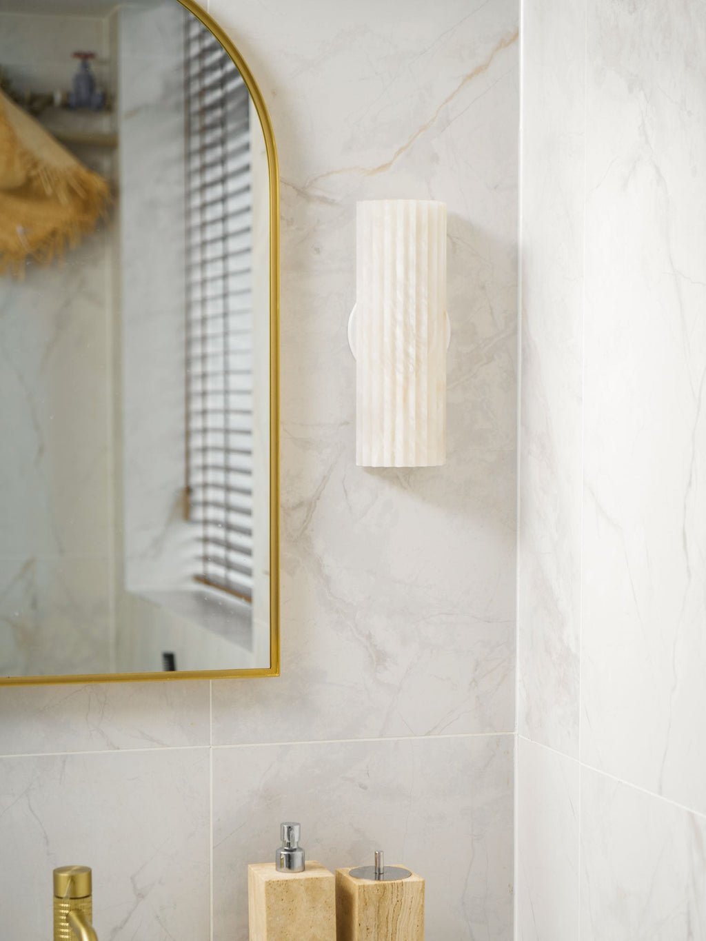 Alabaster wall light glowing softly above a console table