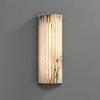 Straight-on view of the lit Orcarion alabaster wall light, showing the full width of its fluted stone face.