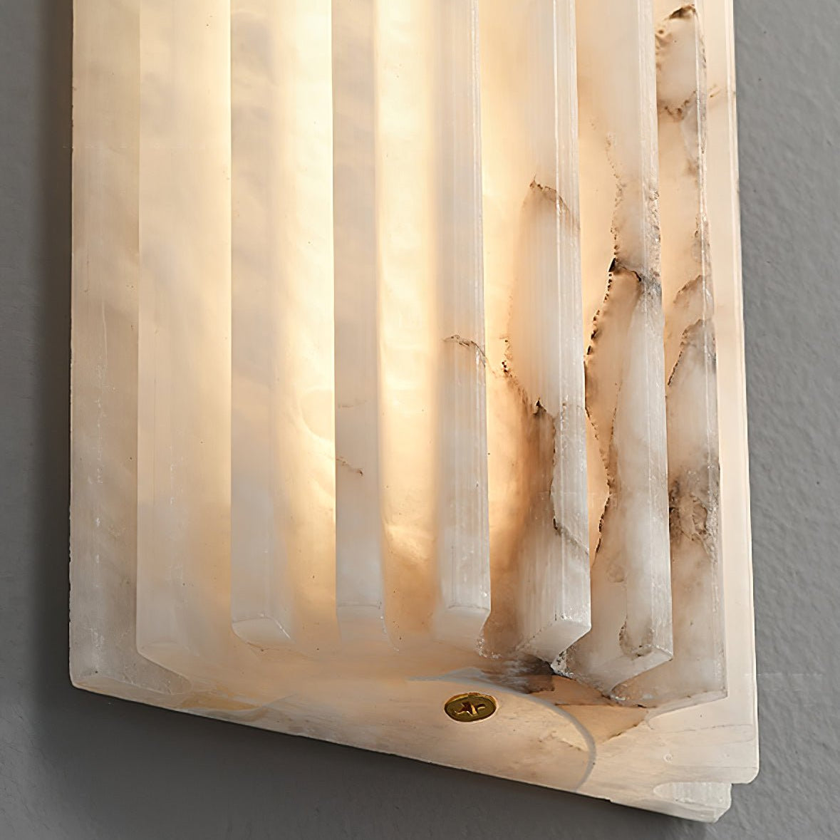 Close-up of the lower corner of the Orcarion wall light, with the small brass fixing screw in the stone base.