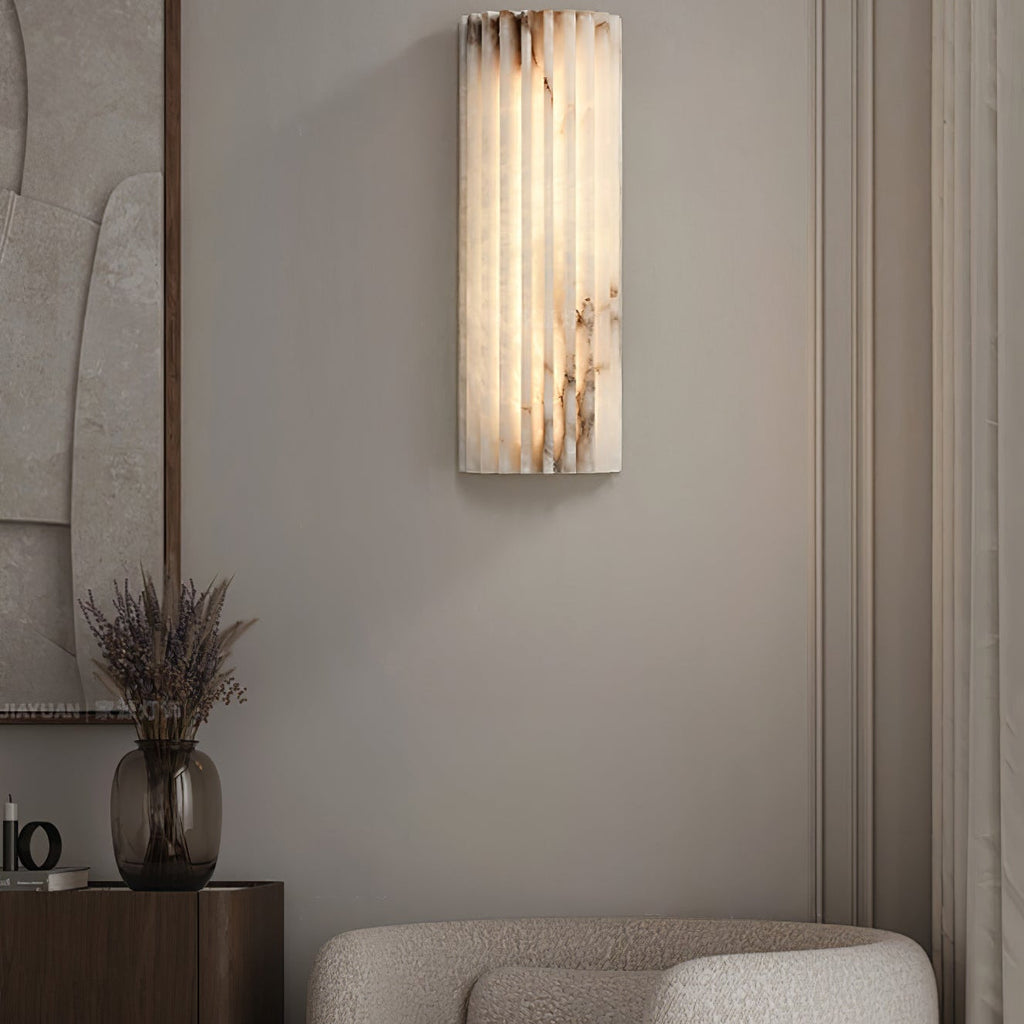 Tighter view of the lit Orcarion wall light in a living room, its stone veining picked out by the glow.