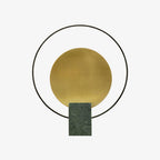 Clérachic table lamp shown from the same straight-on angle, its black ring and gold disc set against white.