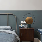 Clérachic table lamp on a wooden nightstand next to an industrial metal-frame bed, a small figurine and glass beside it.