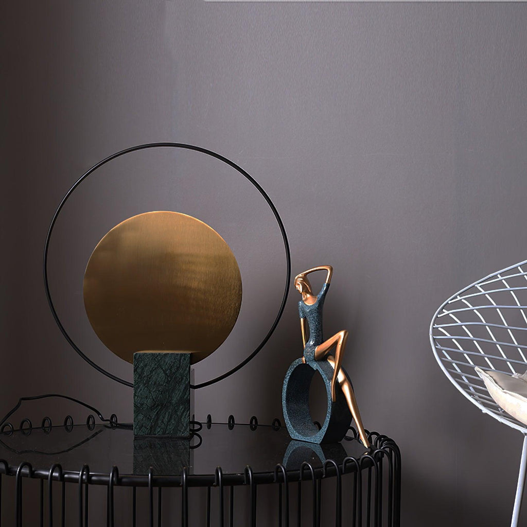 Clérachic table lamp beside a bronze reclining-figure sculpture, both set on a round wire-frame side table.