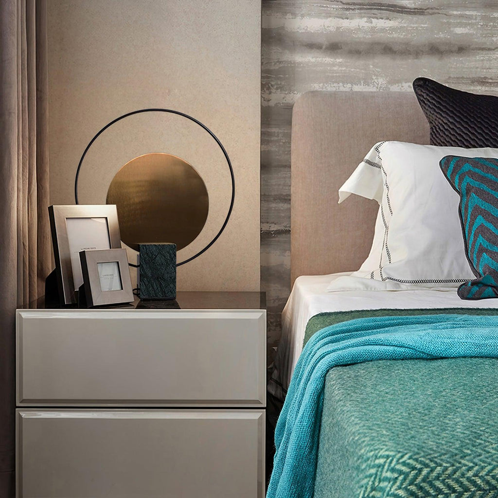 Clérachic table lamp on a bedside dresser next to a small photo frame, a teal throw draped over the bed alongside.