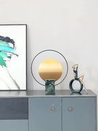 Clérachic table lamp on a blue-grey sideboard beside a framed abstract print and a small bronze figurine.