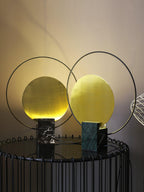 Two Clérachic table lamps, black marble and green marble finishes, glowing together against a dark wall at night.