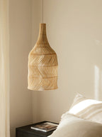 In a bedroom corner, this Clérachic pendant hangs near a bed with white linens and a dark nightstand.