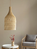 This Clérachic pendant hangs near a grey armchair and a side table holding a small vase of red flowers.