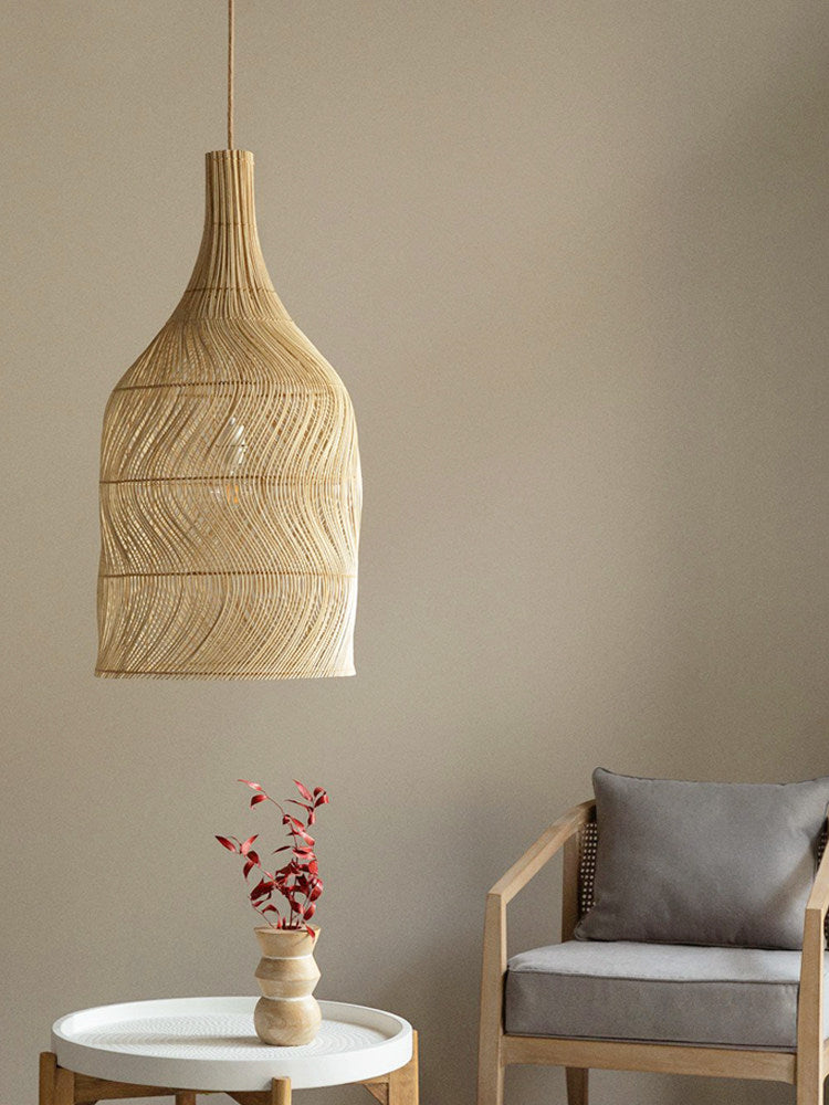 This Clérachic pendant hangs near a grey armchair and a side table holding a small vase of red flowers.