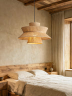 Beneath a wood-beamed ceiling, this Clérachic pendant lights a bedroom dressed in linen bedding and sheer curtains.