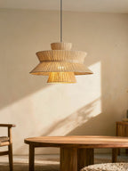 Sunlight falls across this Clérachic pendant as it hangs above a round wood table and a woven chair.