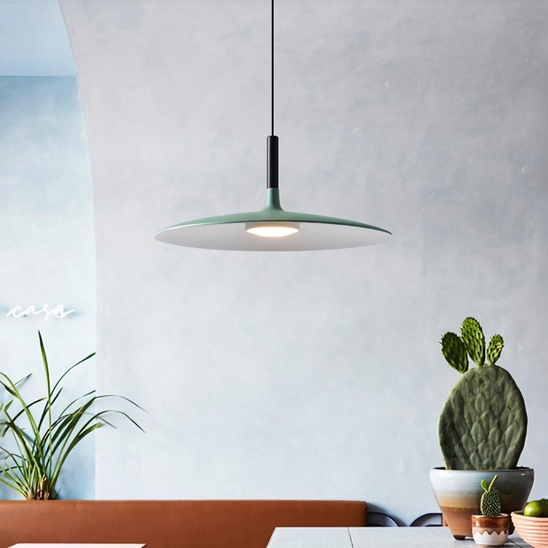Pendant light with aluminum shade lit above a seating area