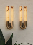 Close-up of two lit bronze Arch sconces showing the brushed U-bend and small knurled fixing pin