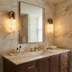 Two bronze Arch wall sconces either side of a bathroom mirror above a marble vanity with brass taps