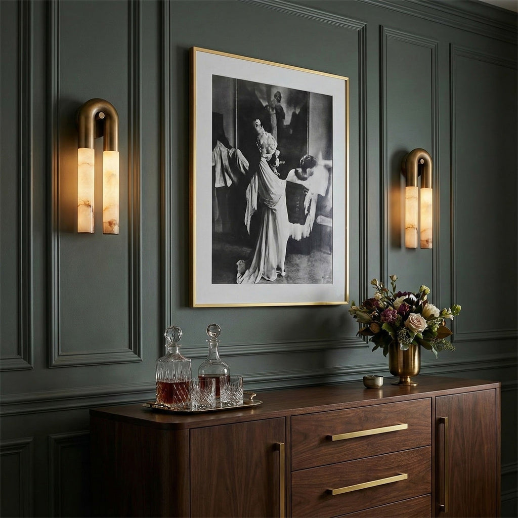 Pair of bronze Arch wall sconces flanking a framed photograph on a dark green panelled wall above a sideboard
