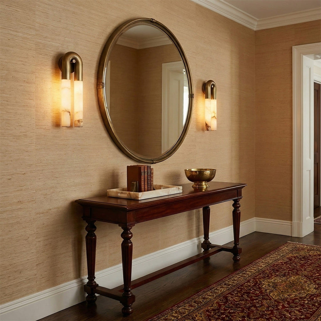 Bronze Arch wall sconces either side of a round mirror above a hallway console table