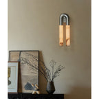 Nickel Arch wall sconce hung arch-up above a sideboard with leaning framed art and a vase of branches
