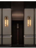 A pair of Arch wall sconces mounted arch-up either side of a dark hotel lift lobby entrance
