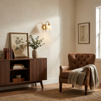 Beside a walnut sideboard with botanical prints, the brass-finish sconce from Clérachic glows above a mid-century armchair.