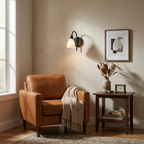 Next to a tan leather armchair and a small side table, this Clérachic sconce's black finish frames an abstract print.