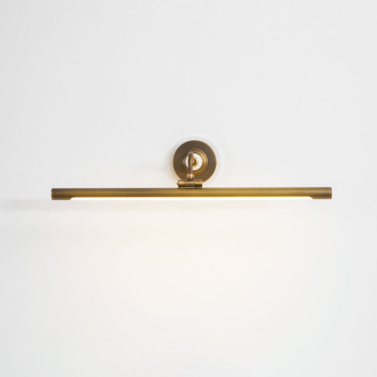 This Clérachic wall sconce in bronze glows softly along its bar, viewed straight-on against a plain white background.