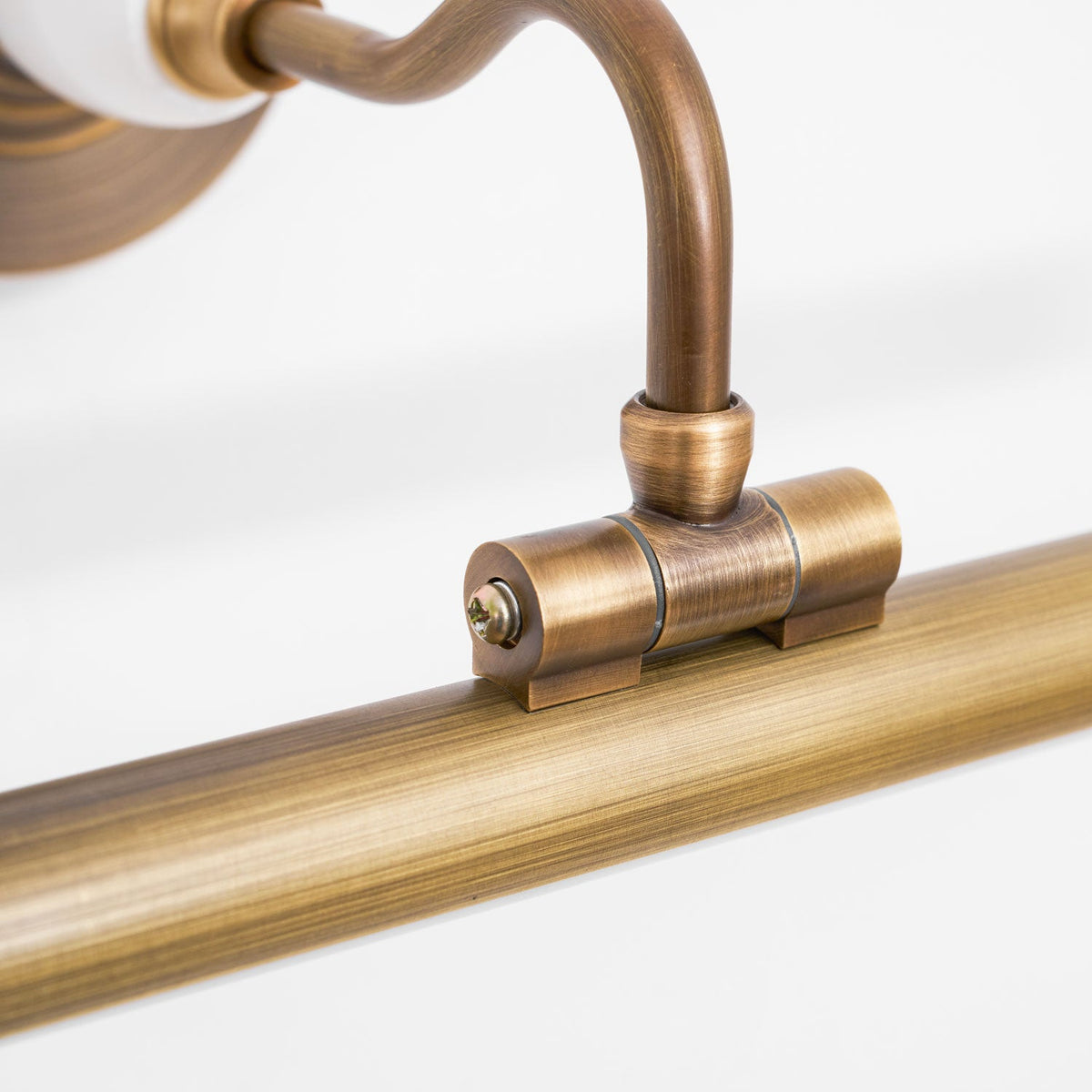 Close view of the curved bronze arm and joint connecting to the bar on this Clérachic wall sconce.