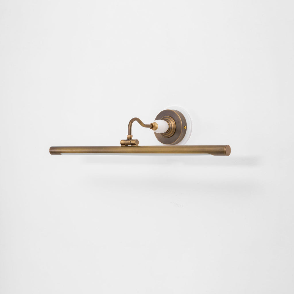 Viewed at an angle on a plain white background, this Clérachic wall sconce in bronze shows its curved arm and slim bar.