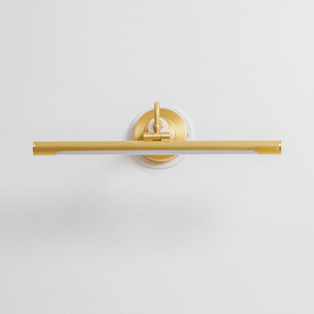 This Clérachic wall sconce in gold sits unlit and straight-on against a plain background, its curved arm and bar in view.