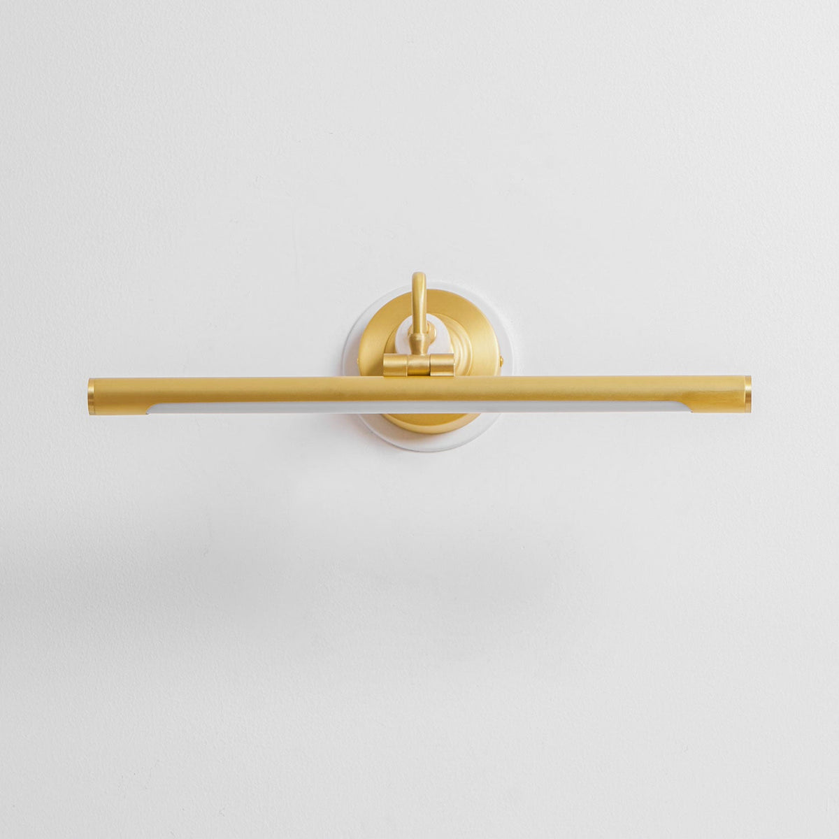This Clérachic wall sconce in gold sits unlit and straight-on against a plain background, its curved arm and bar in view.