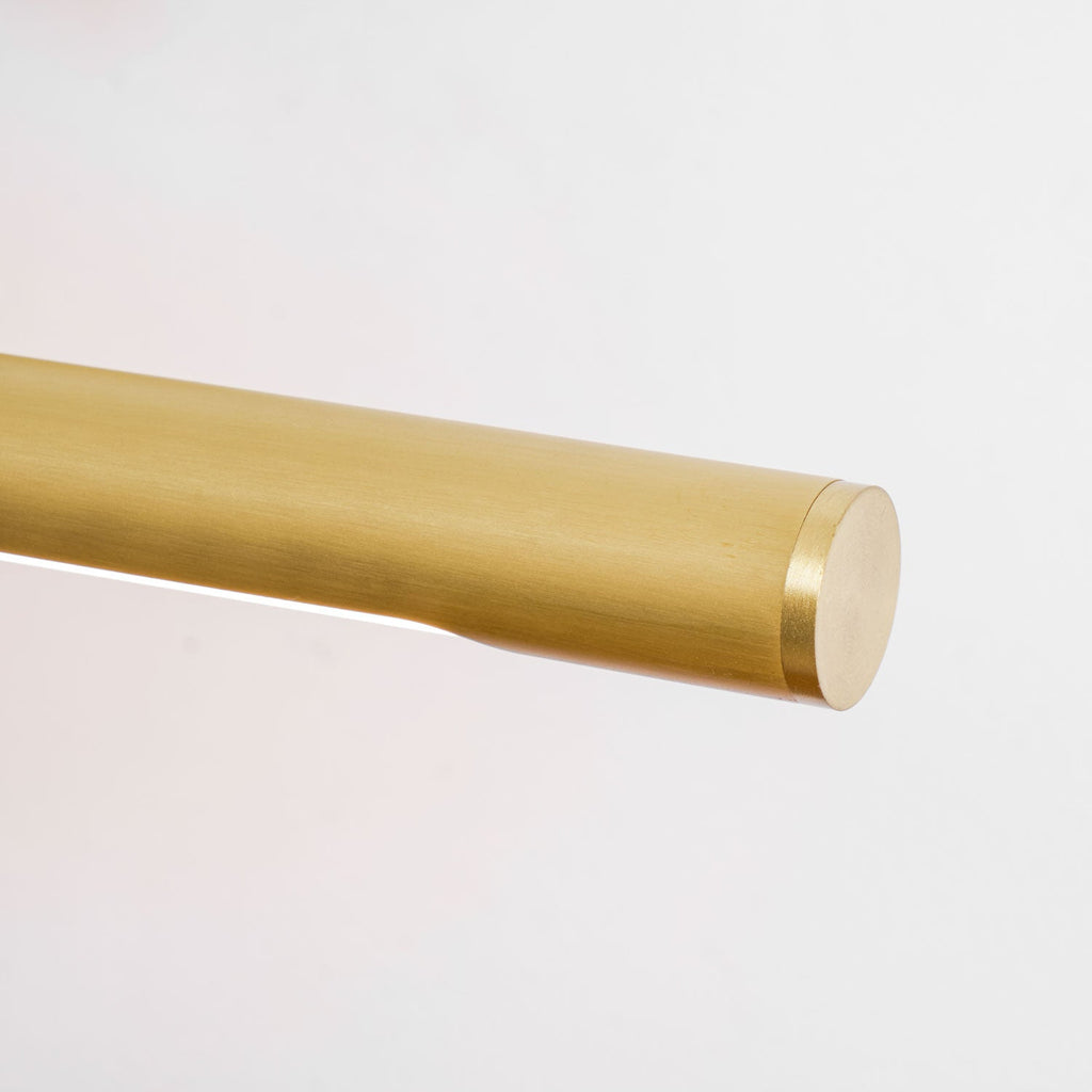 Close view of the slim gold bar on this Clérachic wall sconce, its acrylic shade lit along its length.