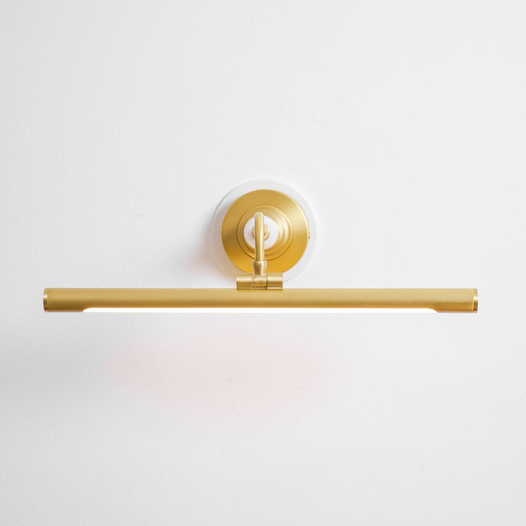 This Clérachic wall sconce in gold sits unlit against a plain background, viewed from a low angle.
