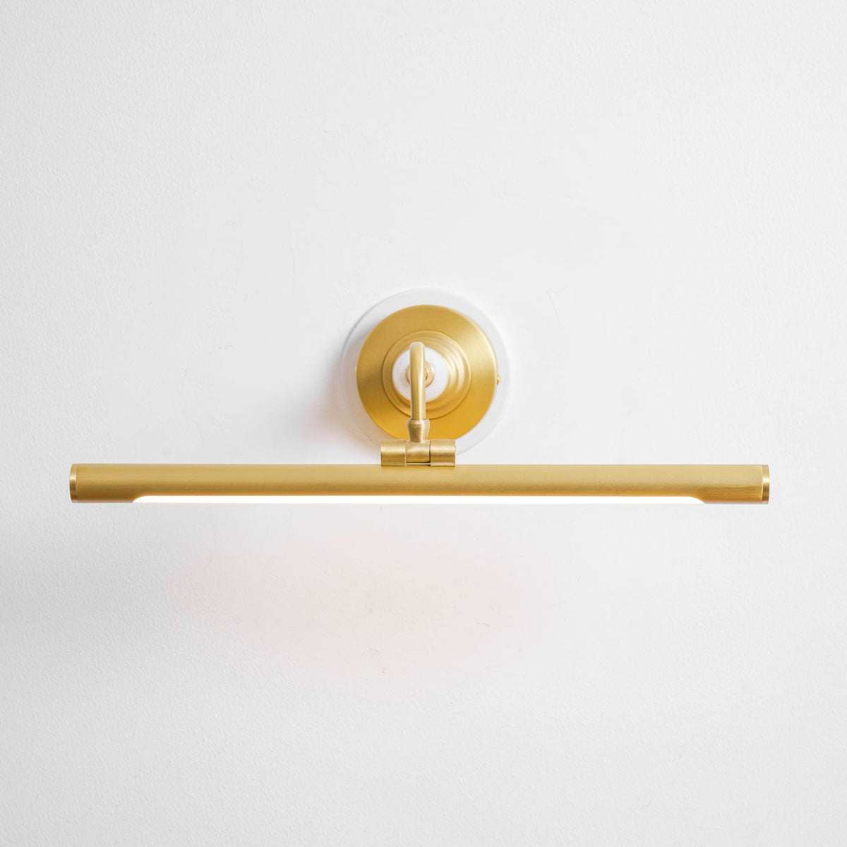 This Clérachic wall sconce in gold sits unlit against a plain background, viewed from a low angle.