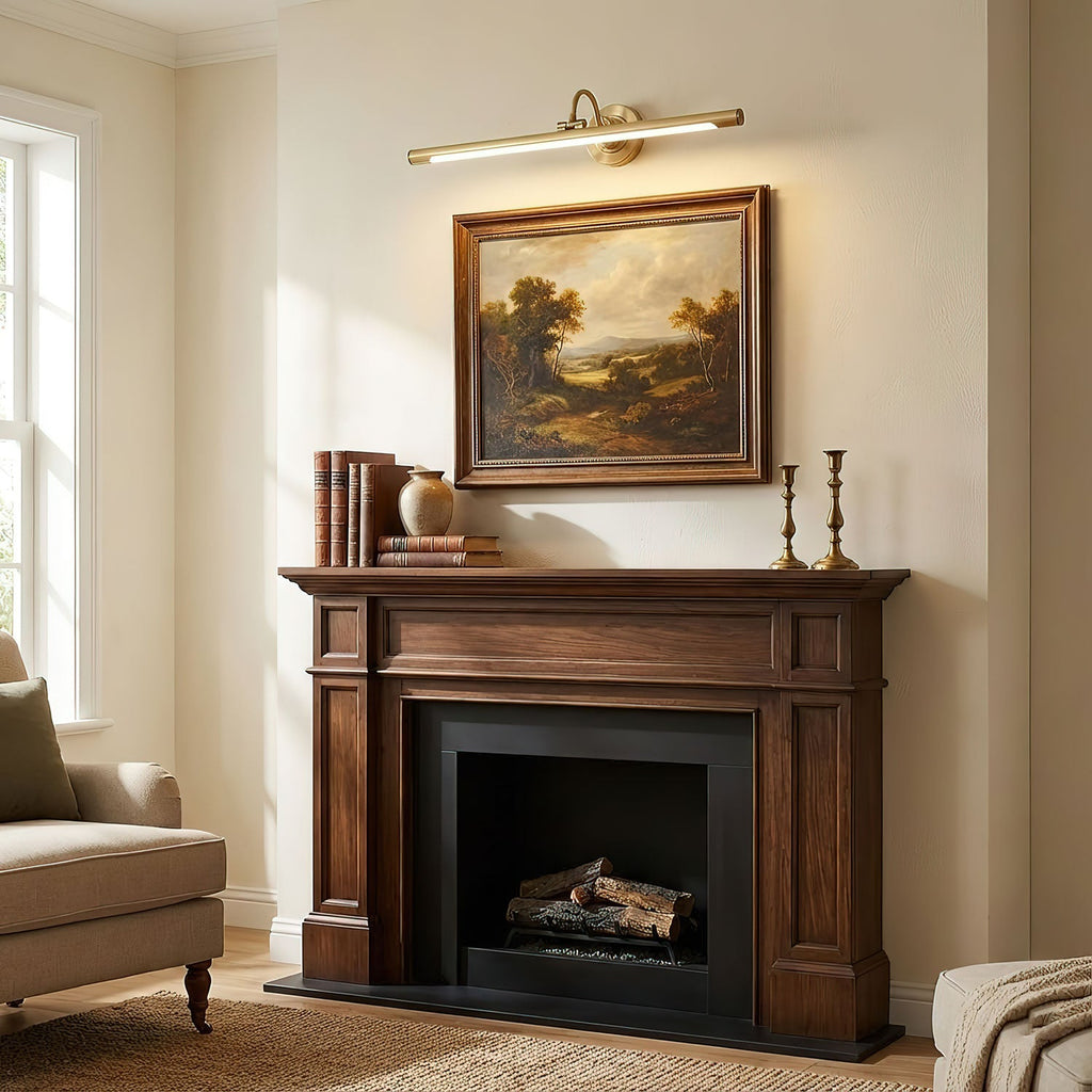 A landscape painting above a wooden fireplace mantel sits in the warm wash of this gold Clérachic wall sconce.