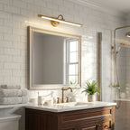 Lit above a mirror in a white subway-tiled bathroom, this Clérachic wall sconce in gold washes warm light across the glass.