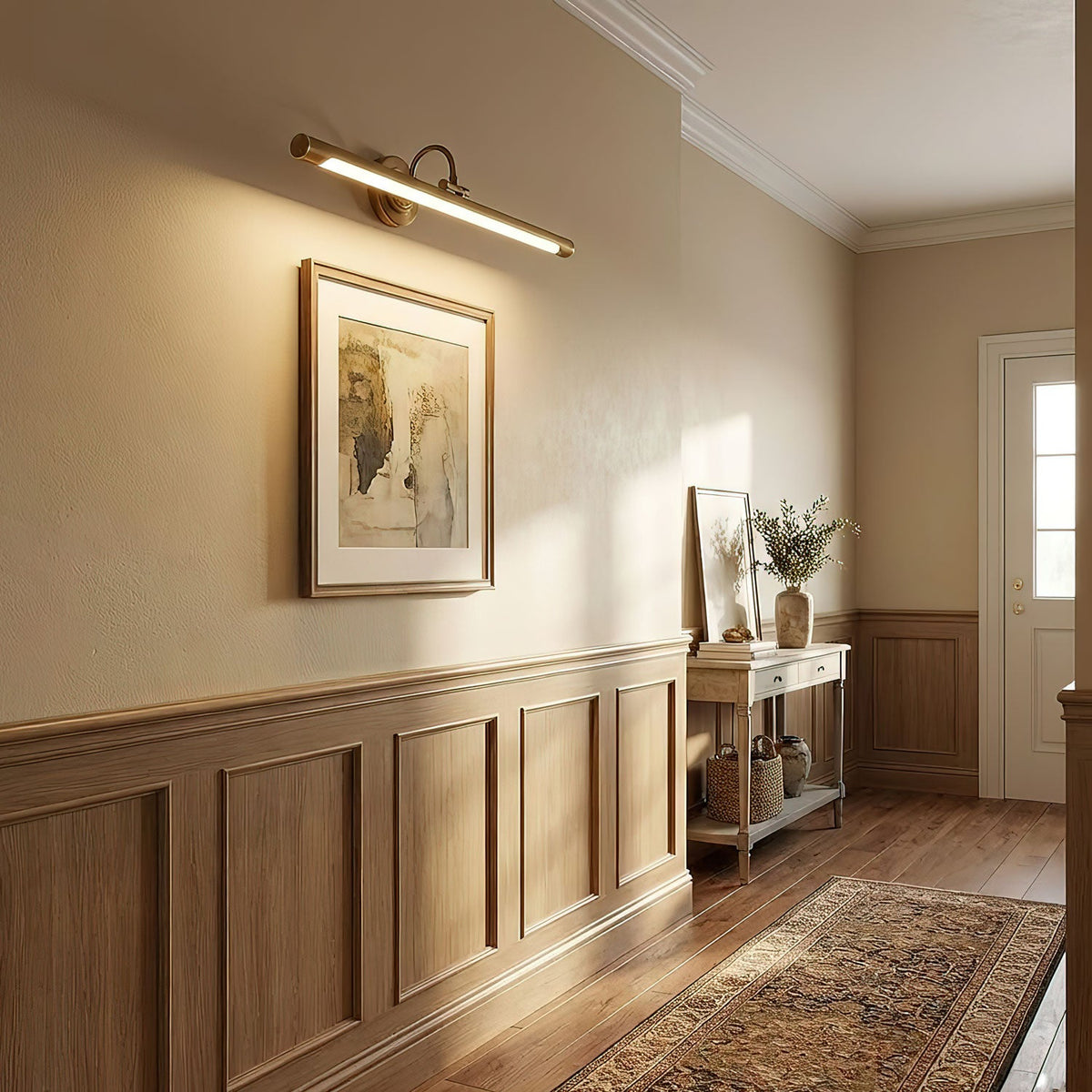 In a hallway with wood wainscoting and a patterned runner, this gold Clérachic wall sconce lights a framed artwork.