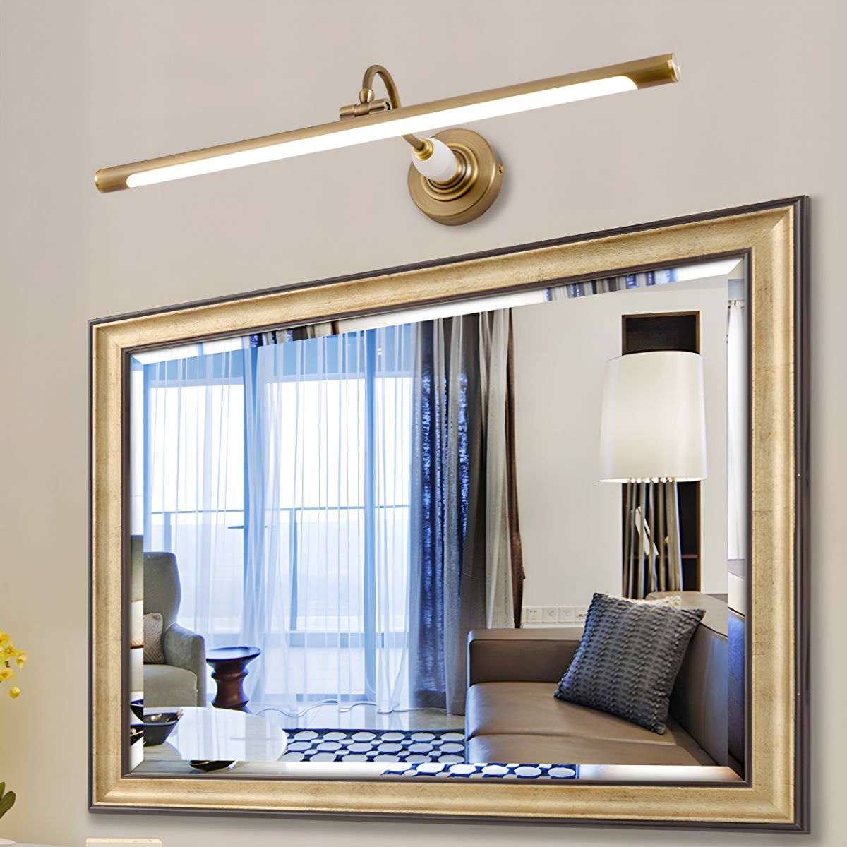 A large ornate mirror, reflecting a sitting room with a floor lamp and sofa, is lit by this gold Clérachic wall sconce.