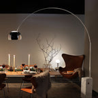 Candlelight and the Clérachic arc lamp's dome light a dressed dinner table, with a leather egg chair and faux fur throw nearby.