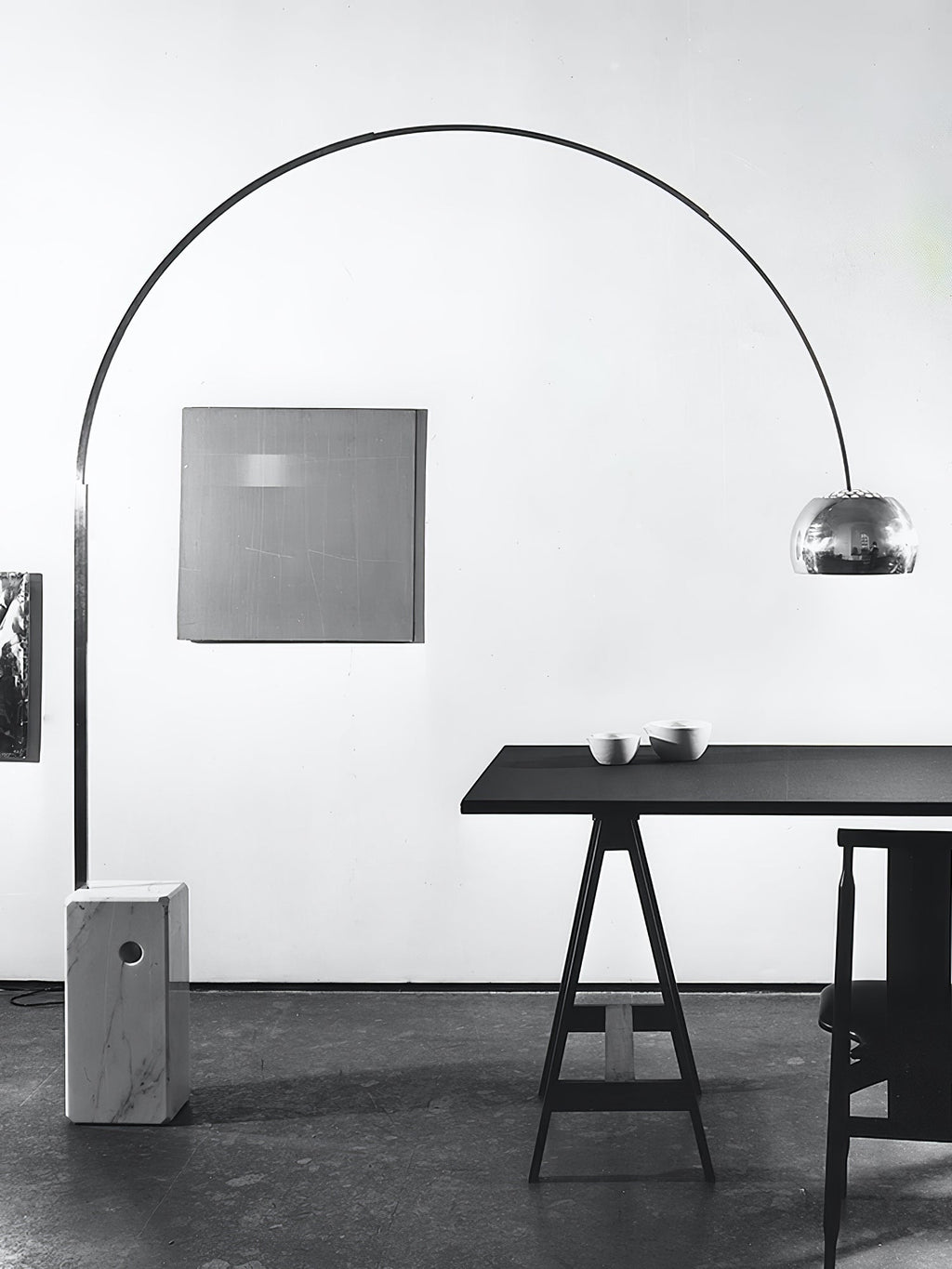 An archival black-and-white shot of the Clérachic arc lamp's steel arch beside a square painting and a dark sawhorse table.