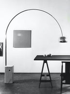 An archival black-and-white shot of the Clérachic arc lamp's steel arch beside a square painting and a dark sawhorse table.
