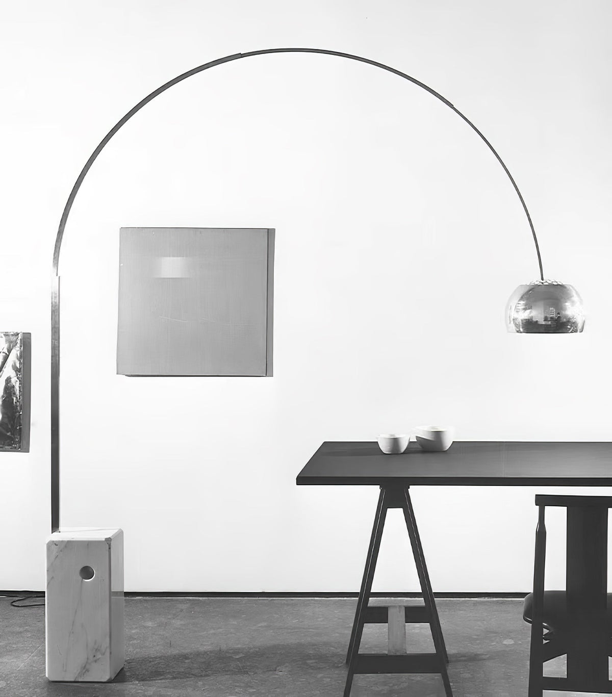 Another angle of the same black-and-white scene shows the Clérachic lamp's chrome dome closer to the sawhorse dining table.